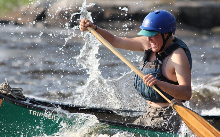 a person navigates whitewater in a canoe